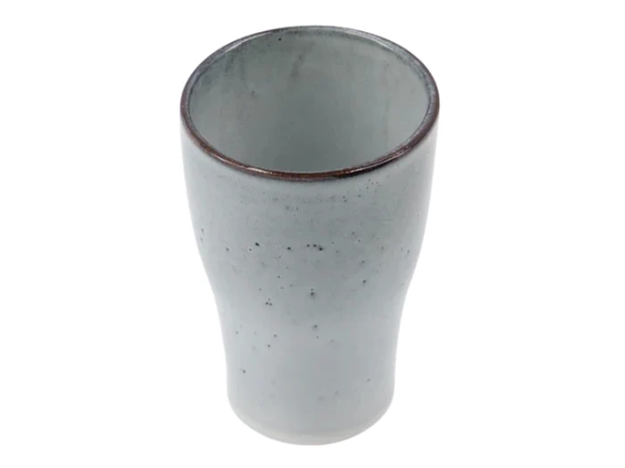 En keramisk kop med en let udsvajet kant, lysegrå glasur, subtile pletter og en glat tekstur, fotograferet på en hvid baggrund.