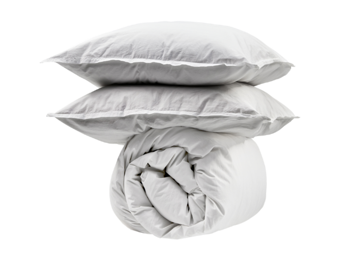 To hvide puder stablet oven på en sammenrullet hvid dyne, alt sammen placeret mod en almindelig hvid baggrund.