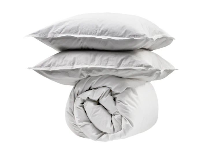 To hvide puder stablet oven på en sammenrullet hvid dyne, alt sammen placeret mod en almindelig hvid baggrund.