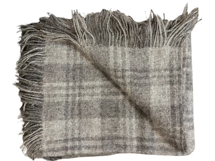 Gråt og beige ternet uldtæppe med frynsede kanter, delvist foldet for at vise begge sider.