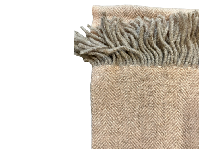 Et beige uldtørklæde med et diskret sildebensmønster og frynsede kanter, vist på en hvid baggrund.