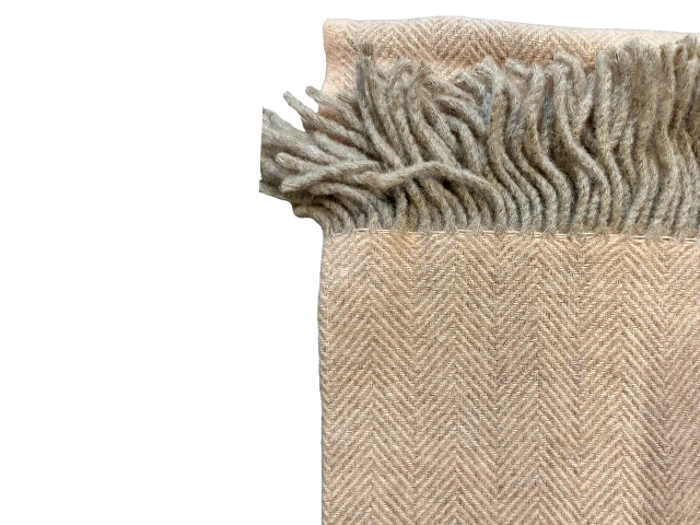 Et beige uldtørklæde med et diskret sildebensmønster og frynsede kanter, vist på en hvid baggrund.