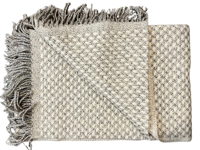 Et foldet, struktureret beige og gråt vævet tæppe med frynsede kanter, der er lagt ud for at vise både for- og bagsidemønstre.