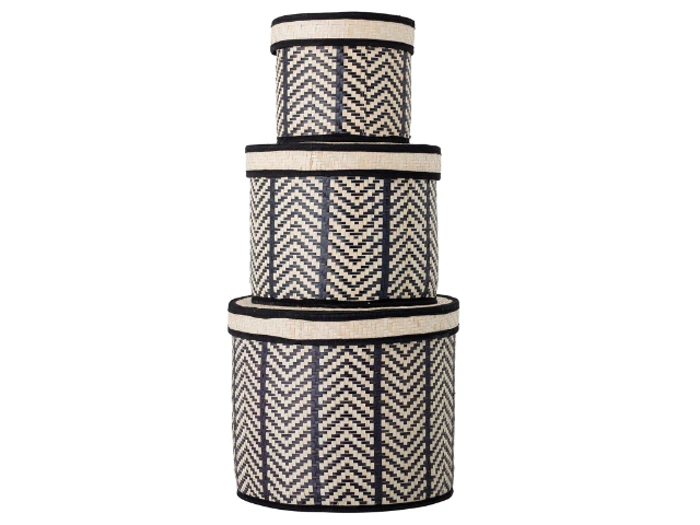 Tre runde, flettede opbevaringskurve i forskellige størrelser er stablet, hver med et zigzag-mønster i sort og natur og matchende låg.