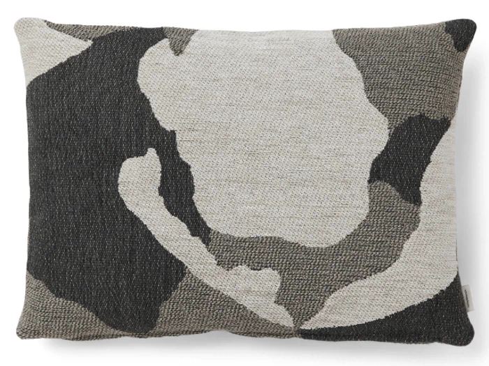 En rektangulær pude med et struktureret stof i abstrakte, camouflageagtige mønstre i sort, grå og råhvid.