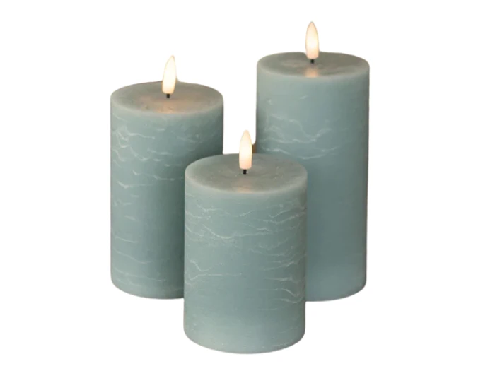 Tre tændte blå bloklys i forskellige højder er arrangeret sammen mod en hvid baggrund.