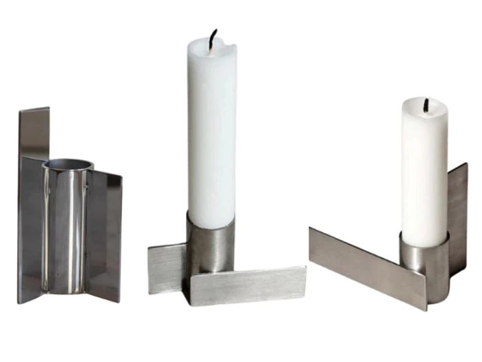 Tre billeder af en moderne lysestage i sølvfarvet metal med et minimalistisk, geometrisk design, hvor der står et hvidt lys.