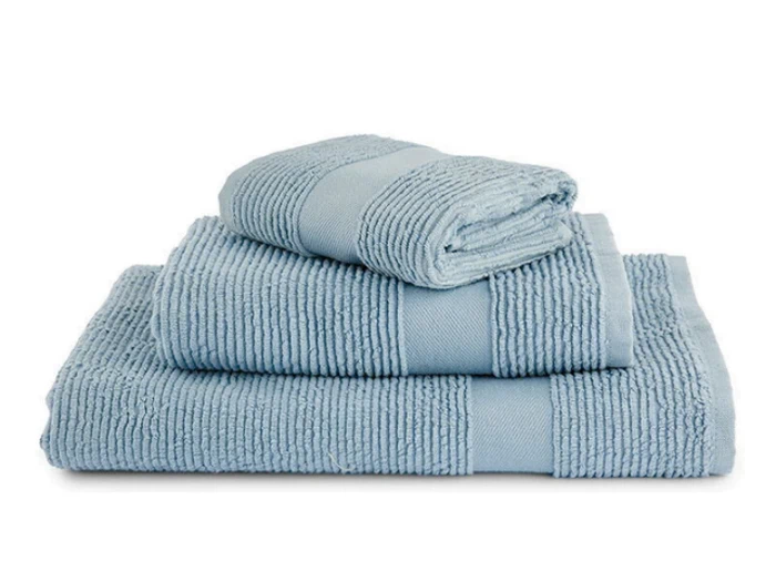 Tre lyseblå, pænt foldede håndklæder i forskellige størrelser stablet oven på hinanden med et struktureret, ribbet mønster og ensfarvede bånd.