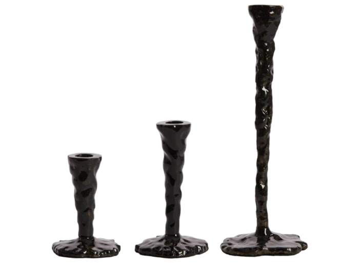 Tre sorte, uregelmæssigt formede lysestager i forskellige højder er arrangeret side om side mod en hvid baggrund.
