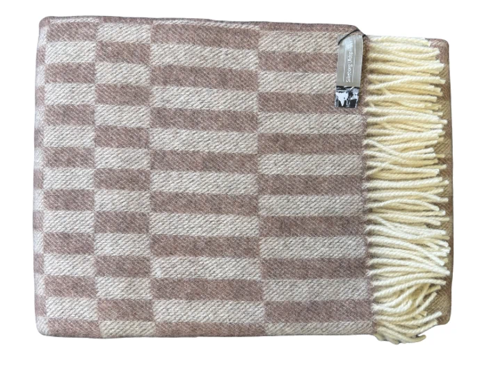 Et foldet beige- og brunternet uldtæppe med cremefarvede frynser på den ene side og en lille etiket i hjørnet.