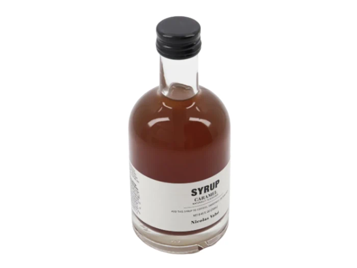 En glasflaske med sort låg, der indeholder brun sirup. På den hvide etiket på flasken står der "SYRUP", og der er yderligere mindre tekst nedenunder.