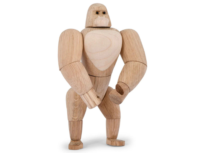 En gorillafigur af træ med bevægelige led står oprejst mod en almindelig hvid baggrund.