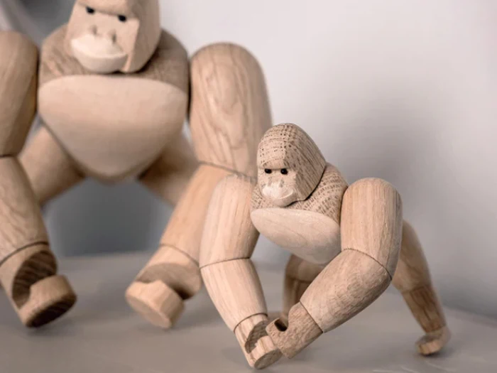 To gorillafigurer af træ, en stor og en lille, begge med leddelte lemmer og udskårne ansigtstræk, placeret som om de går på alle fire.