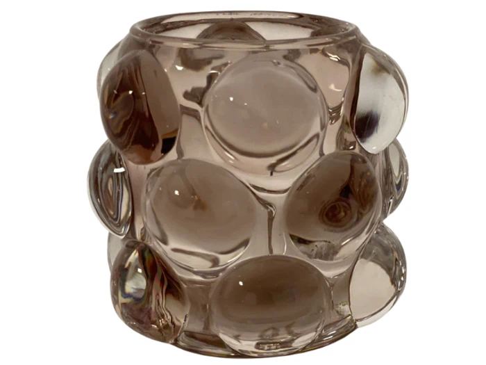 En klar glasvase med store, hævede boblelignende mønstre, der dækker overfladen, fotograferet mod en hvid baggrund.