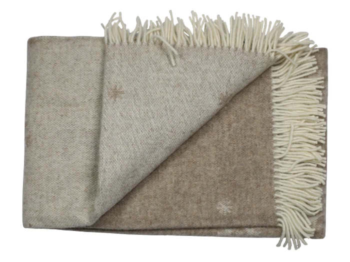 Et foldet beige uldtæppe med cremefarvede frynser langs den ene kant, vist på en hvid baggrund.