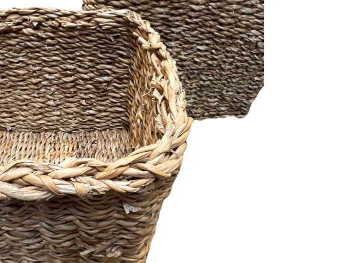 Nærbillede af to flettede stråkurve med en flettet kant på en hvid baggrund. Den ene kurv overlapper delvist den anden.