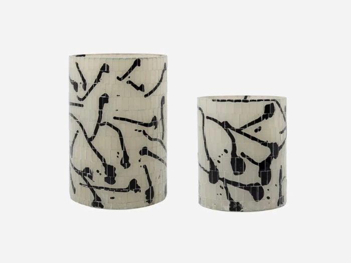 To cylindriske vaser med hvid bund og abstrakte sorte mønstre, placeret side om side på en ensfarvet baggrund.