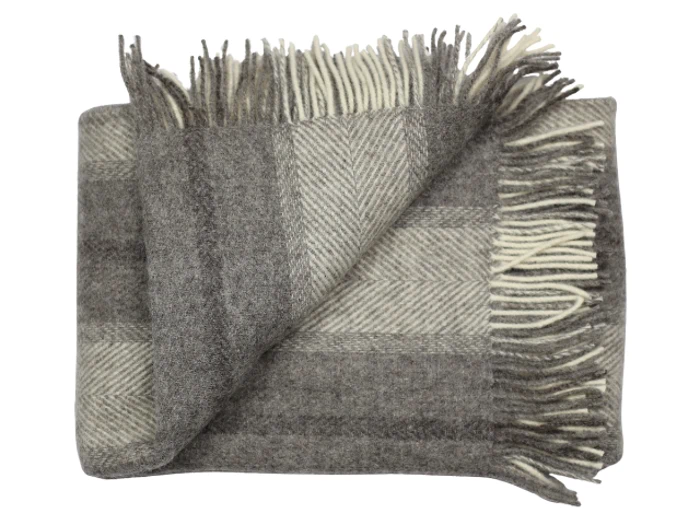 Et foldet, uldtæppe i grå og beige nuancer med frynsede kanter.