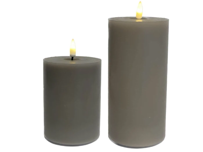 To grå bloklys i forskellige højder med små gule flammer, der står oprejst side om side på en hvid baggrund.