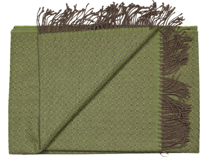 Et foldet grønt tekstureret stof med små diamantmønstre og brune frynser langs kanterne.
