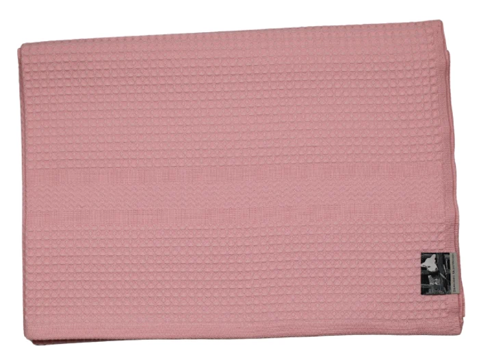 Et foldet pink håndklæde med vaffelstruktur og et lille sort-hvidt mærke i det ene hjørne.