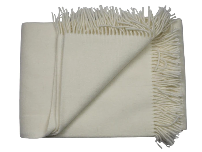 Et foldet cremefarvet uldtæppe med frynsede kanter, sirligt arrangeret på en almindelig baggrund.