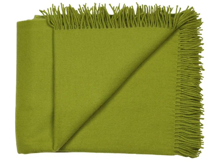 Et grønt uldtæppe med frynser på den ene kant, pænt foldet med det ene hjørne vendt om for at vise strukturen og de frynsede detaljer.