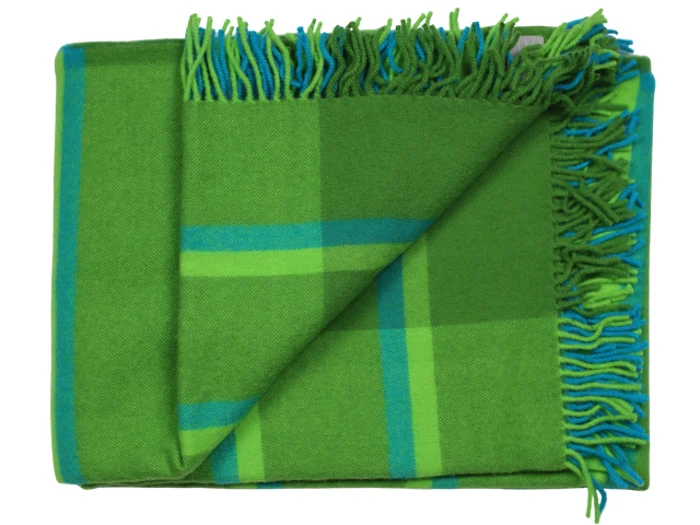 Et foldet grønt tæppe med blåt og lysegrønt ternet mønster og frynser langs den ene kant.