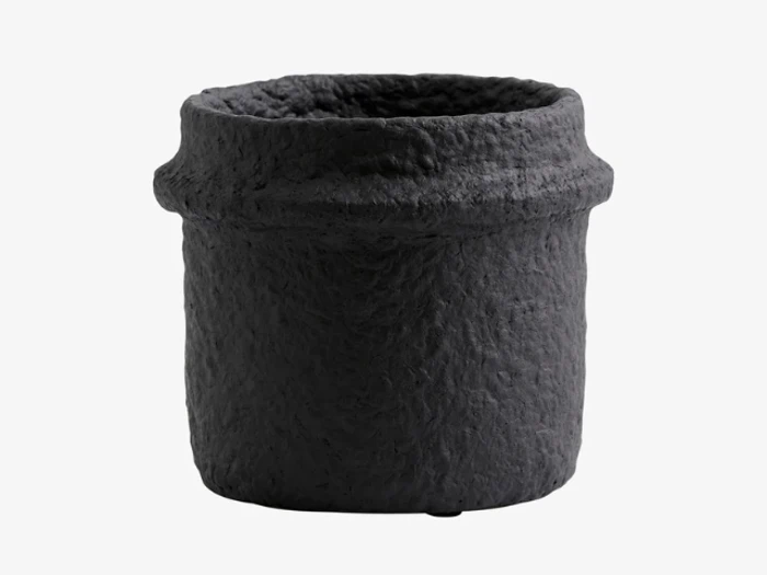 En rund, sort, struktureret urtepotte med en ru, ujævn overflade og en let udvidet kant mod en almindelig hvid baggrund.