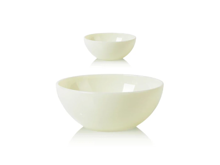To enkle hvide keramikskåle, en stor i forgrunden og en mindre i baggrunden, placeret på en hvid flade med en refleksion.