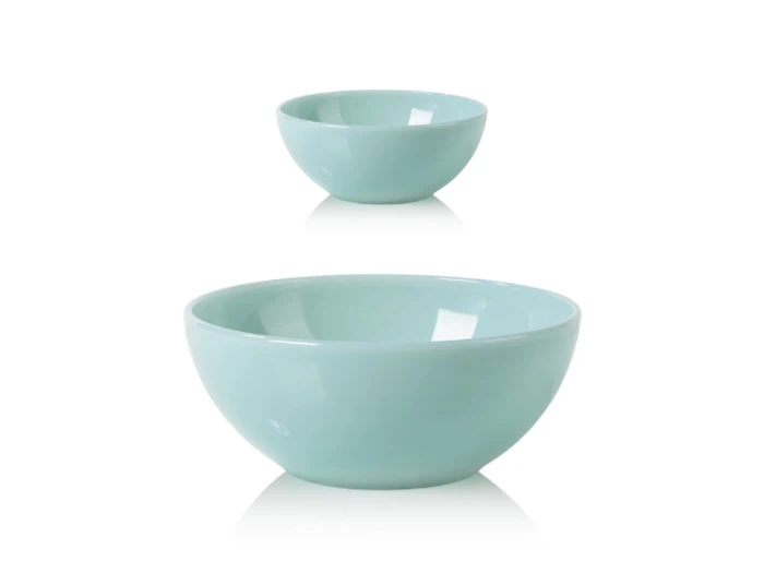 To lyseblå keramikskåle i forskellige størrelser er placeret på en hvid baggrund med den lille skål bag den store.