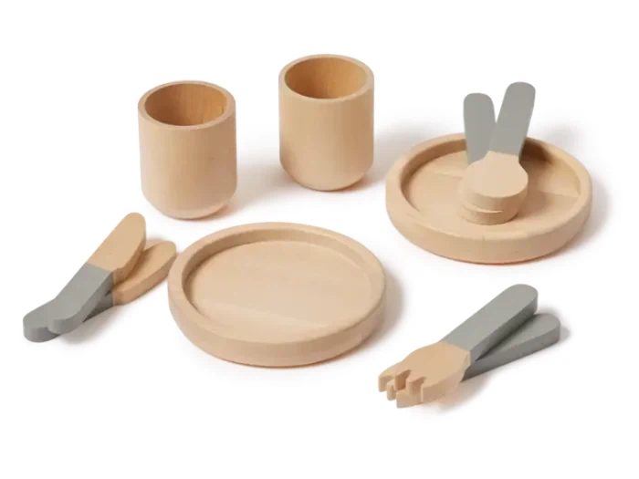 Et sæt legetøjsfade i træ indeholder to kopper, en tallerken, en delt tallerken, to knive, to gafler og to skeer i naturtræ og grå farver.