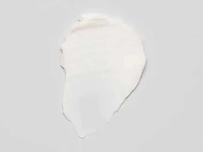 En klat hvid creme eller lotion på en almindelig lysegrå baggrund.