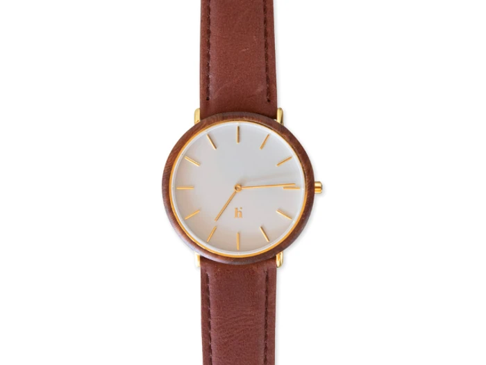 Et minimalistisk armbåndsur med hvid urskive, guldmarkører og en brun læderrem, vist fra oven.