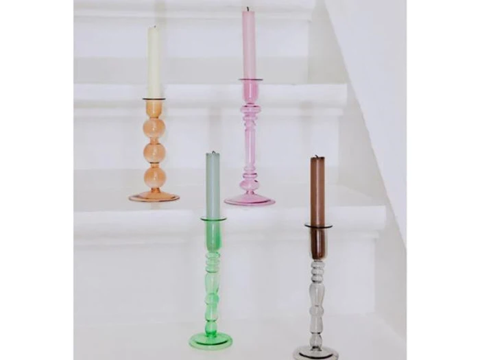 Fire farverige glaslysestager med stearinlys - orange, pink, grøn og klar - står på hvide trin.