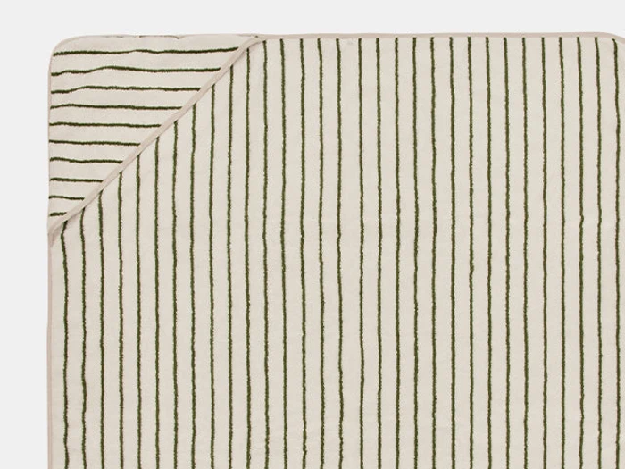 Et rektangulært beige håndklæde med tynde, ujævne grønne lodrette striber. Det øverste venstre hjørne er foldet og viser bagsiden med diagonale grønne striber.