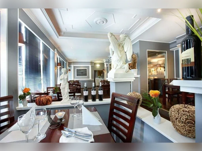Denne elegante restaurant er indrettet med klassiske statuer, vinflasker, moderne indretning, hyggelige træstole og friske blomster på bordene, hvilket skaber en raffineret og indbydende atmosfære, de