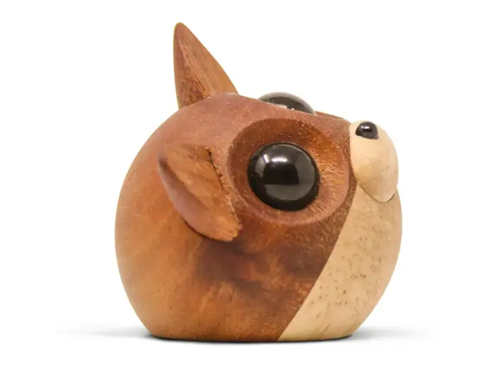 En rund træfigur af en ræv med store sorte øjne, spidse ører og en lille snude på en hvid baggrund.