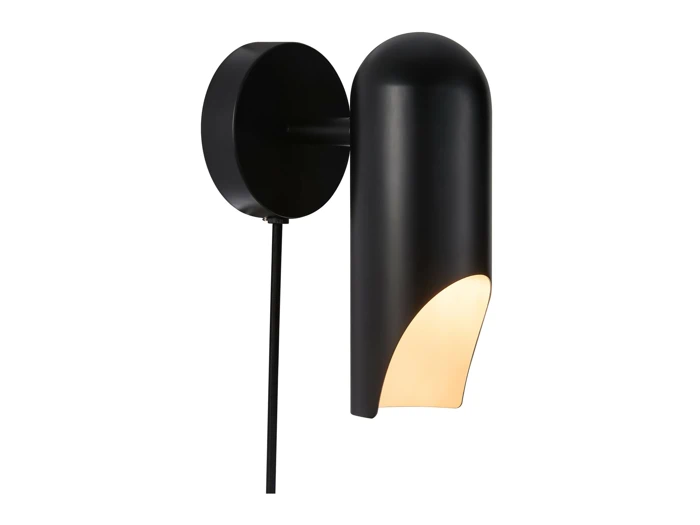En moderne sort væglampe med en cylindrisk skærm, der er delvist åben i bunden og udsender et varmt lys mod en hvid baggrund.