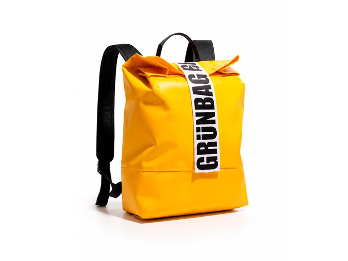 En lysegul rygsæk med sorte stropper og en hvid stroppe foran, hvor der står »GRÜNBAG« med fed sort skrift, vist på en hvid baggrund.