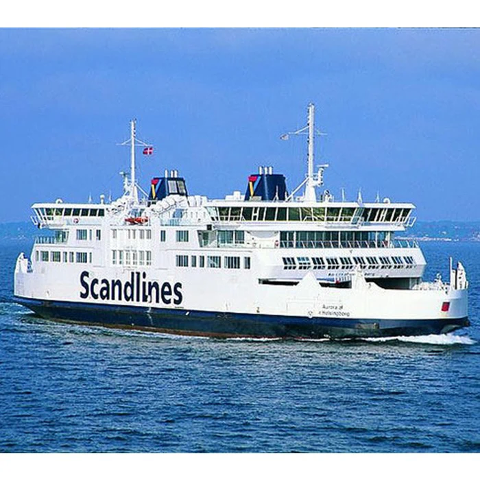 En stor hvid Scandlines-færge sejler på det åbne vand under en klar blå himmel med navnet synligt på siden af skibet.