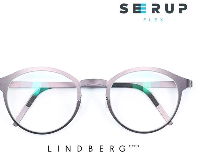 Et par runde, sølvfarvede briller med tyndt stel er centreret på en hvid baggrund. Ordene SEERUP FLEX og LINDBERG står over og under brillerne.