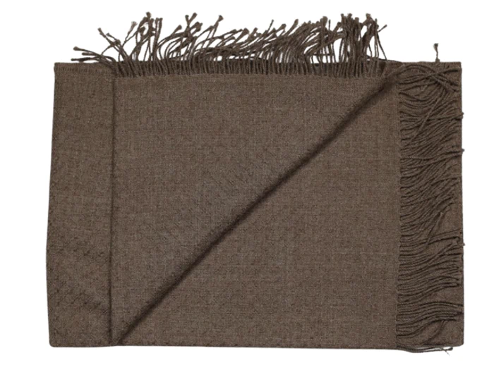 Et brunt vævet tørklæde med frynser på kanterne, foldet pænt på en hvid baggrund.