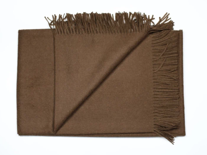 Et foldet brunt uldtørklæde med frynsede kanter, lagt fladt på en hvid overflade.