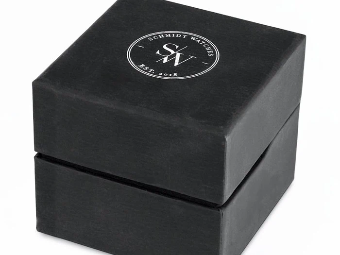 En sort, firkantet urkasse med logoet Schmidt Watches SW Est. 2018 trykt i hvidt på låget.
