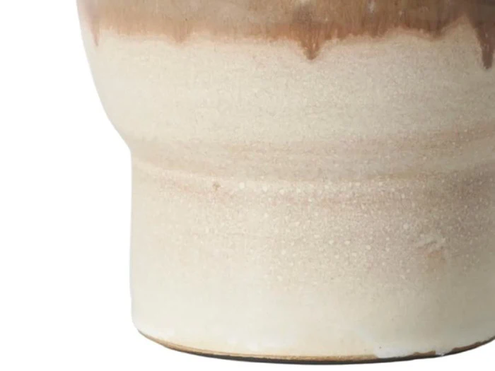 Nærbillede af den nederste del af en keramikvase med en mat beige bund og en blank brun drypglasur nær toppen.