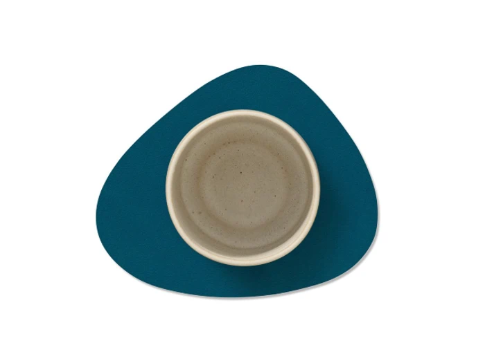 En rund, beige keramikskål står på en blå, uregelmæssigt formet dækkeserviet mod en hvid baggrund.