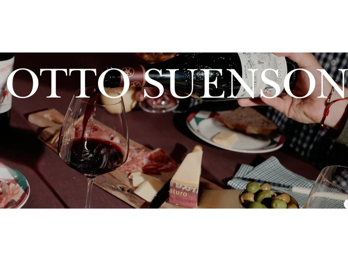 En hånd hælder rødvin op i et glas på et bord med ost, oliven, brød og charcuteri. I stor hvid tekst står der OTTO SUENSON.
