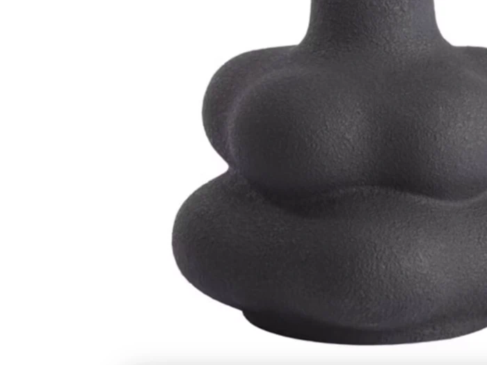 Et nærbillede af et matsort, abstrakt, pæreformet objekt med afrundede, lagdelte kurver mod en hvid baggrund.