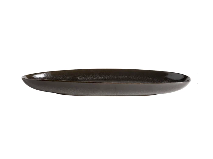 En mørk, oval keramiktallerken med blank overflade, set fra siden mod en hvid baggrund.